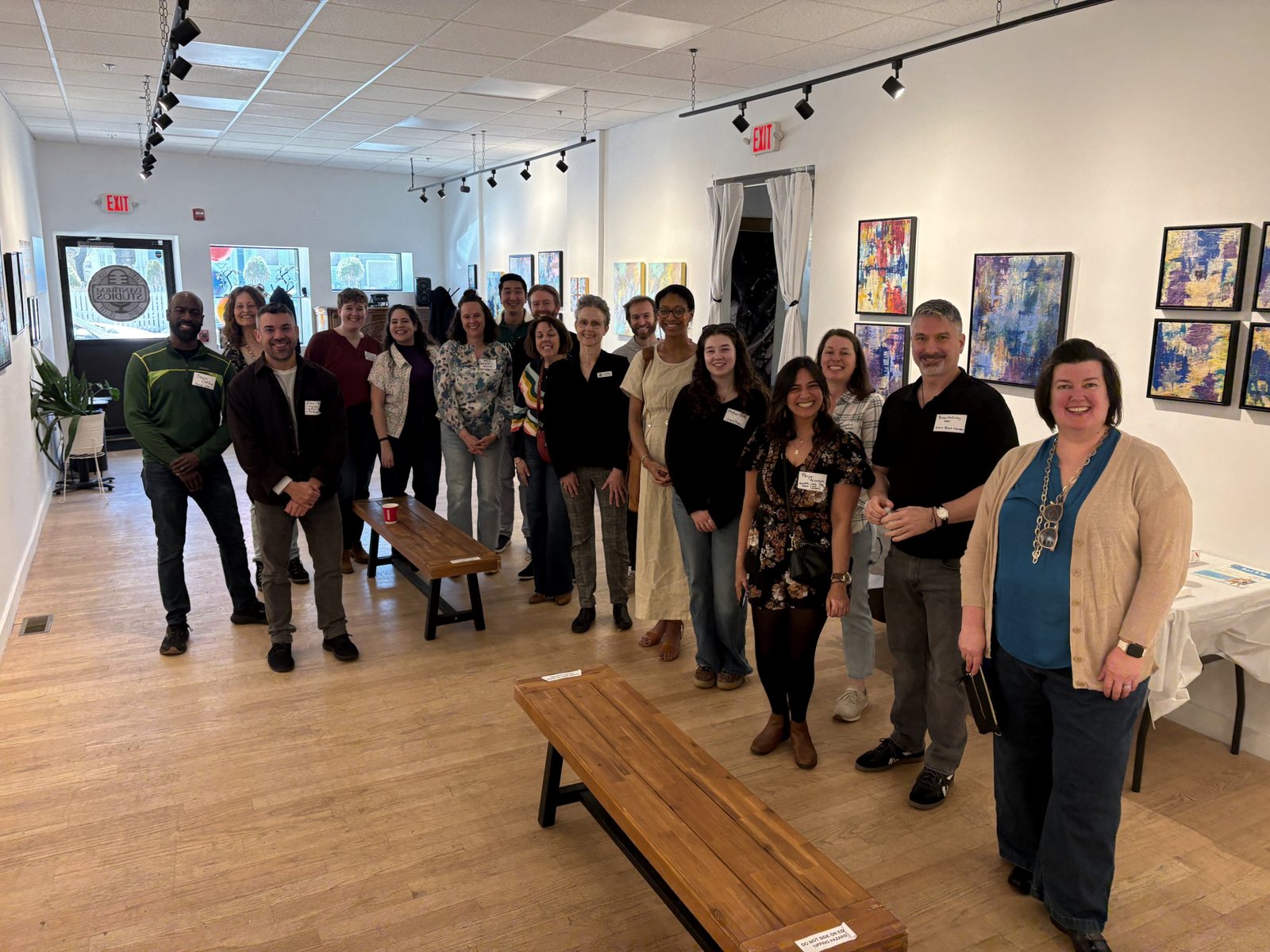 A smiling group gathered at a TMG community event in an art gallery